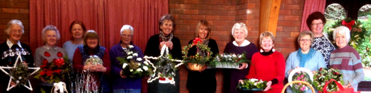 a line of ladies holding Christmas flower arrangements